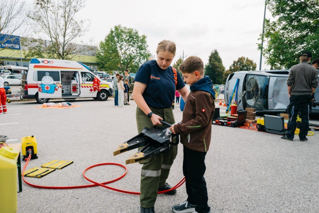 Bub hält gemeinsam mit einer jungen Feuerwehrfrau den hydraulischen Spreizer
