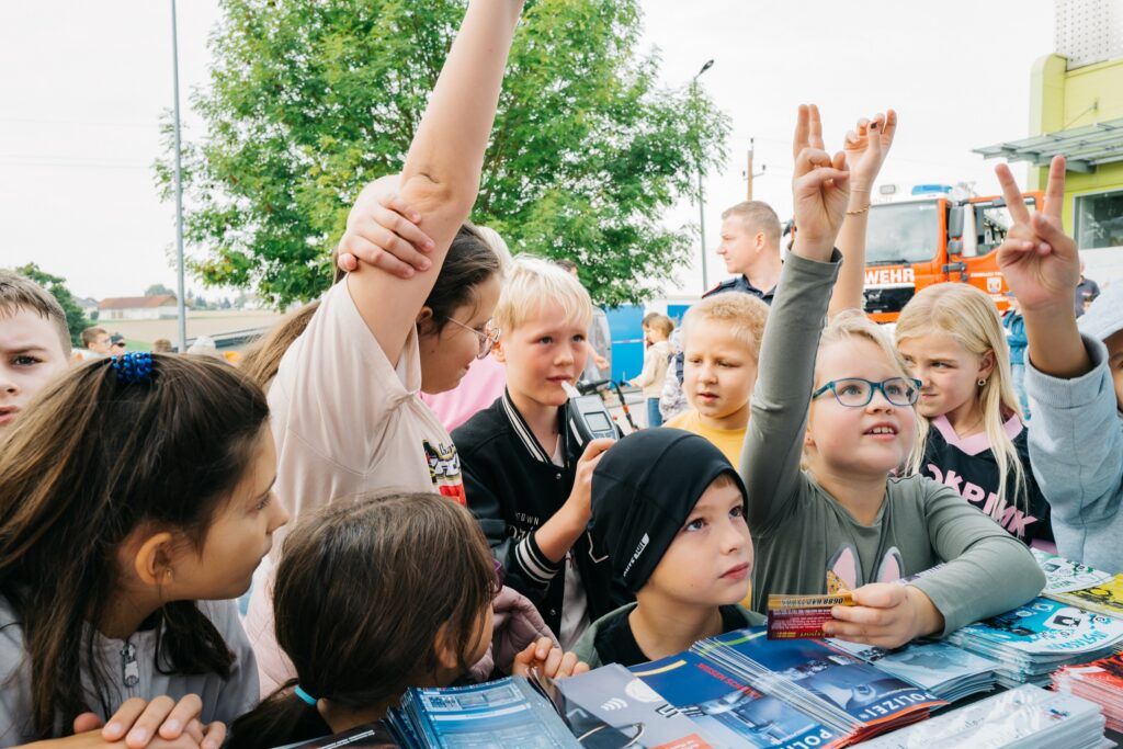 Schulkinder zeigen am Stand der Polizei auf
