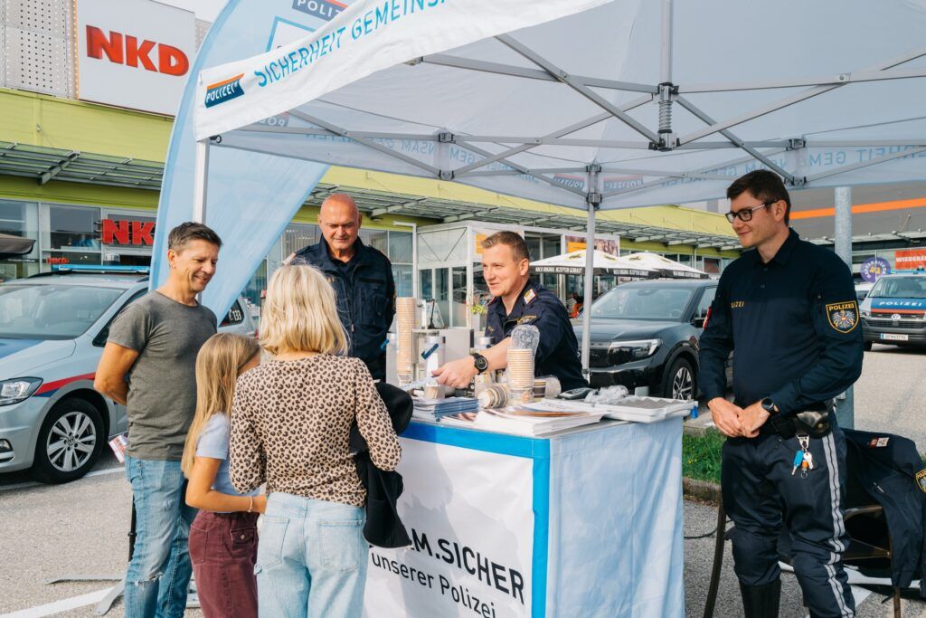 Familie im Gespräch mit Polizisten am Stand der Polizei