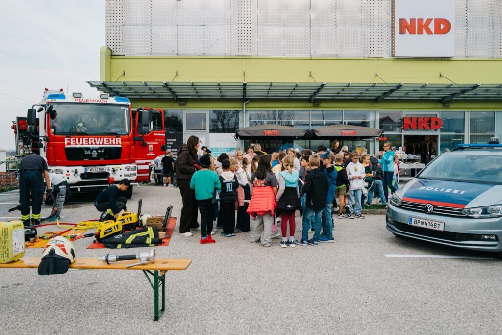 Schulklassen am Parkplatz des City Center Peuerbach zwischen Feuerwehrauto und Polizeiauto