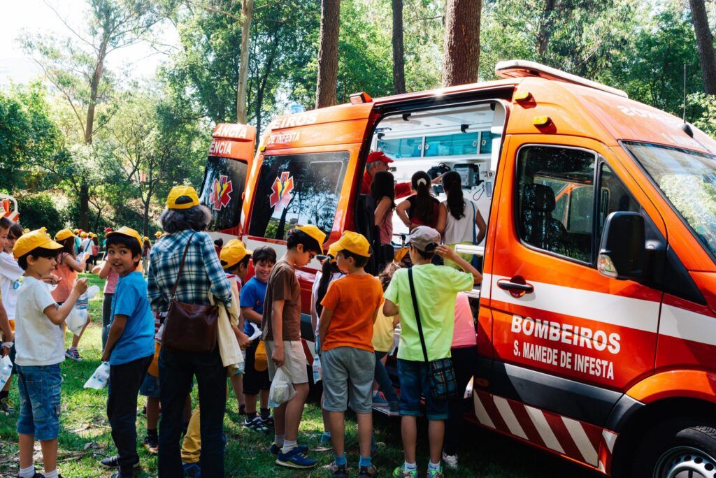 Schulkinder mit gelben Kappen vor einem Fahrzeug der Feuerwehr in Porto
