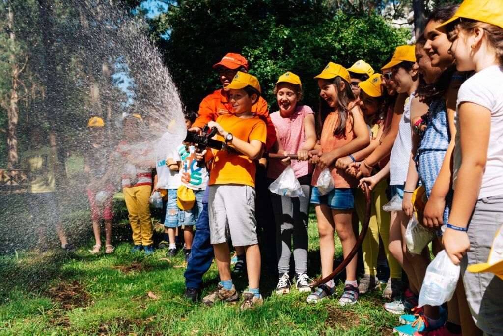 Kinder halten in Porto gemeinsam mit einem Feuerwehrmann den Schlauch